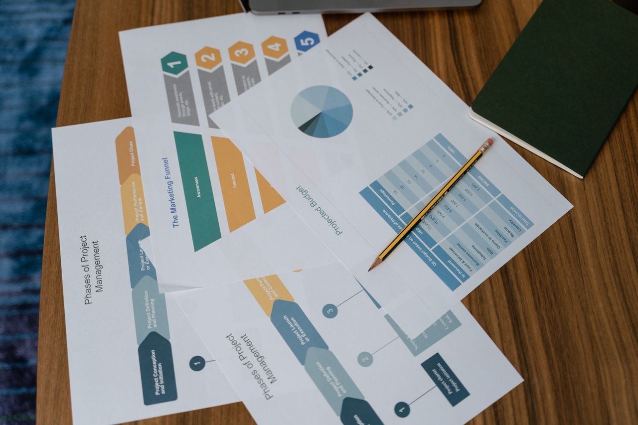 home-hero-bg Overhead view of project management documents and charts on a desk with a pencil.